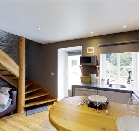 eine Küche mit einem Holztisch und einer Treppe in der Unterkunft Le repaire des amoureux in La-Roche-en-Ardenne