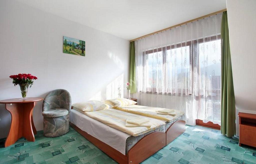 1 dormitorio con cama, mesa y ventana en Willa Slavita, en Zakopane