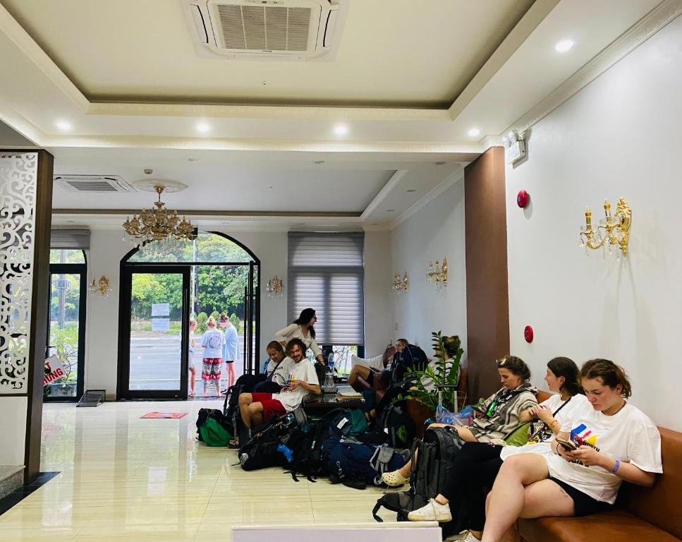 um grupo de pessoas sentadas num átrio a olhar para os seus telefones em De Charm Hạ Long Hotel em Ha Long