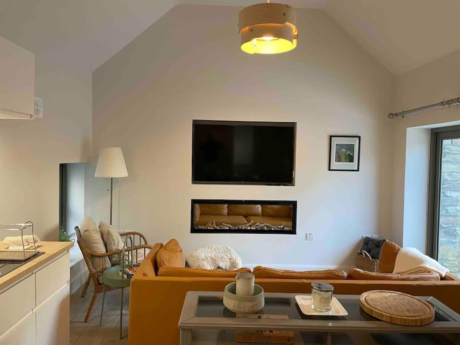 The Coach House, Clonakilty في كلوناكيلتي: غرفة معيشة مع أريكة وتلفزيون بشاشة مسطحة