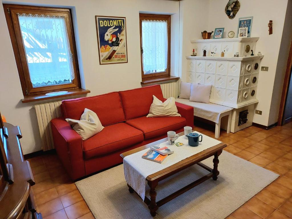 a living room with a red couch and a coffee table at Dalla Dora- A peaceful place in the Dolomites in Villa