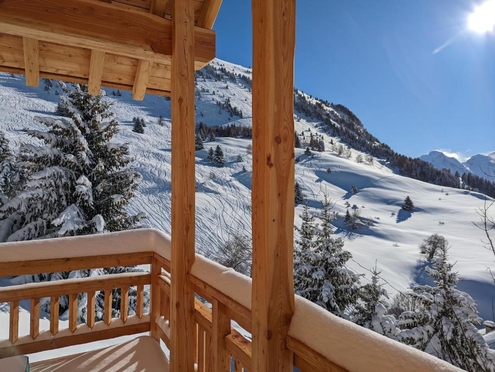 a view from the balcony of a cabin with snow covered mountains at La Boutame : chalet au pied des pistes à Villard Reculas in Villard-Reculas