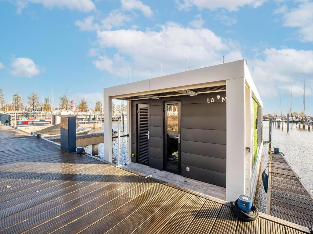 un petit bâtiment sur un quai à côté de l'eau dans l'établissement Inviting houseboat in Volendam with shared pool, à Volendam