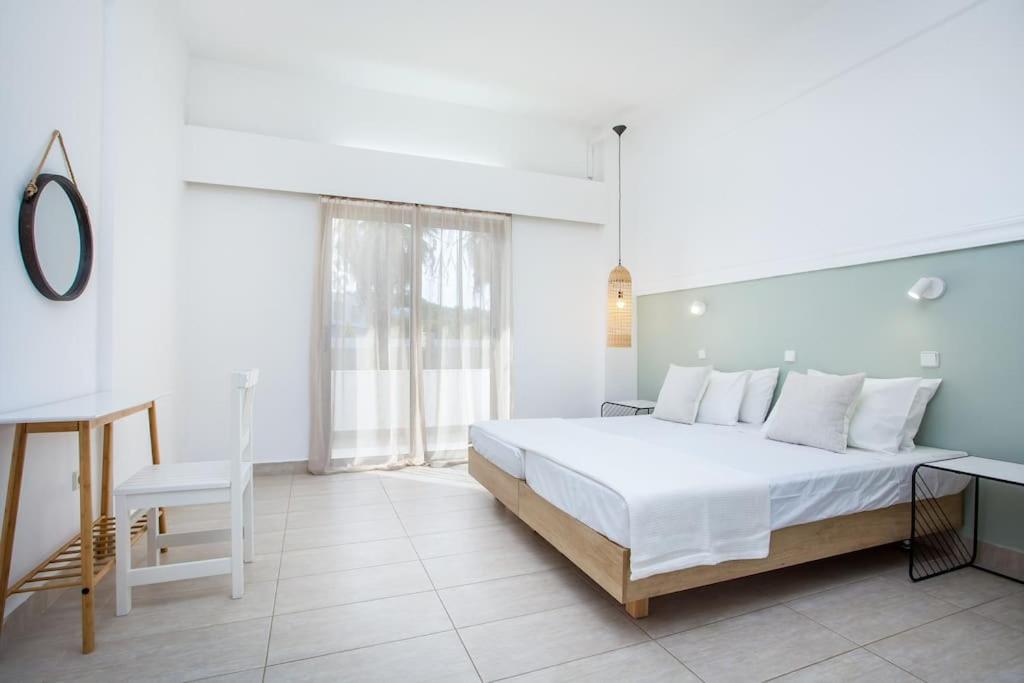 a white bedroom with a large bed and a chair at Rosie's Studio 3 in Faliraki