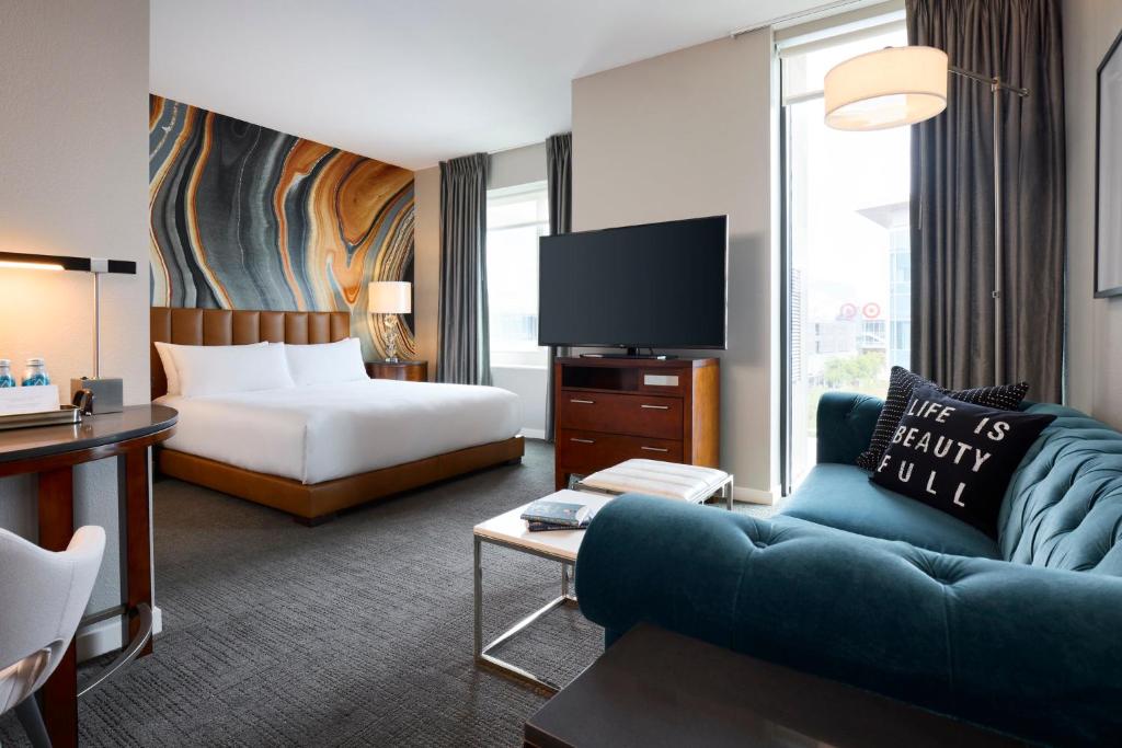 a hotel room with a bed and a couch and a tv at Archer Hotel Falls Church in Fairfax