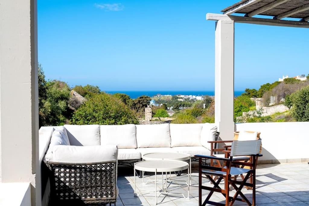 a white couch on a patio with a view of the ocean at Calm & Joy - Poseidonia in Posidhonía