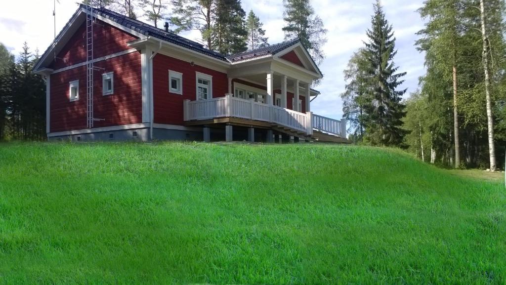 uma casa vermelha no topo de uma colina relvada em Löydön Kartano Villas em Mikkeli