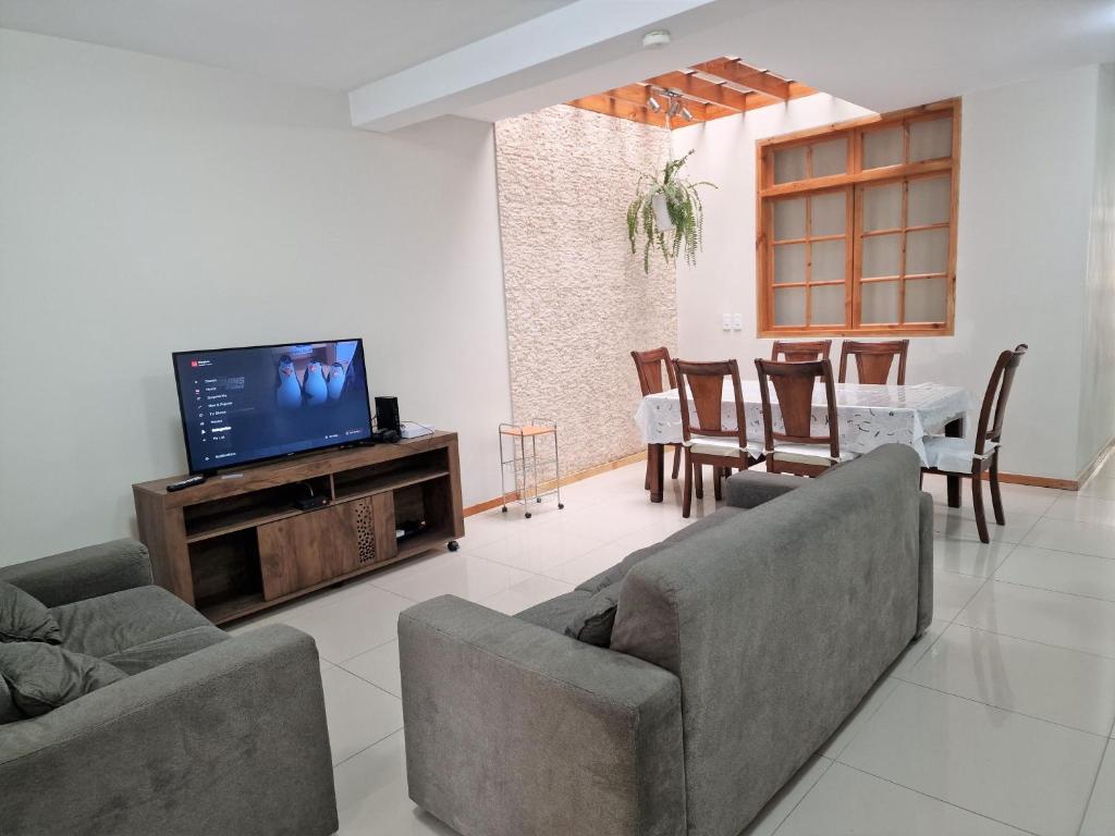 a living room with two couches and a flat screen tv at CASA - Mary Ann's House in Trujillo