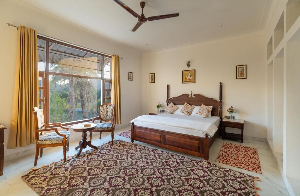 Jass Bagh Home stay Udaipur I swimming pool I wedding I 87oo2o5865 في أودايبور: غرفة نوم بسرير وطاولة ونافذة