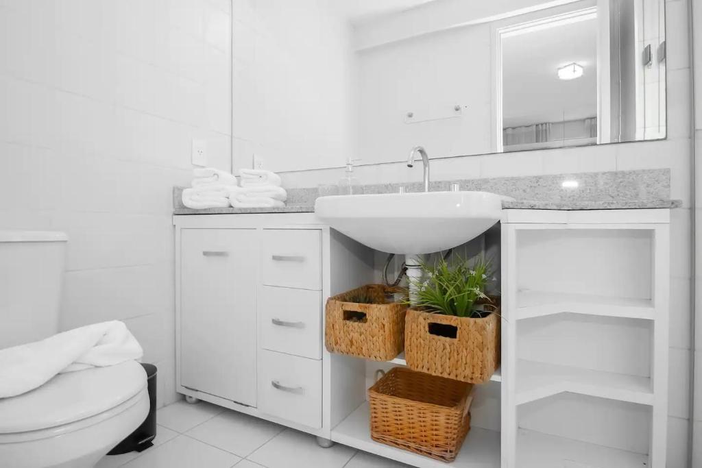 a white bathroom with a sink and a toilet at Apartamento na Berrini próximo ao WTC in Sao Paulo
