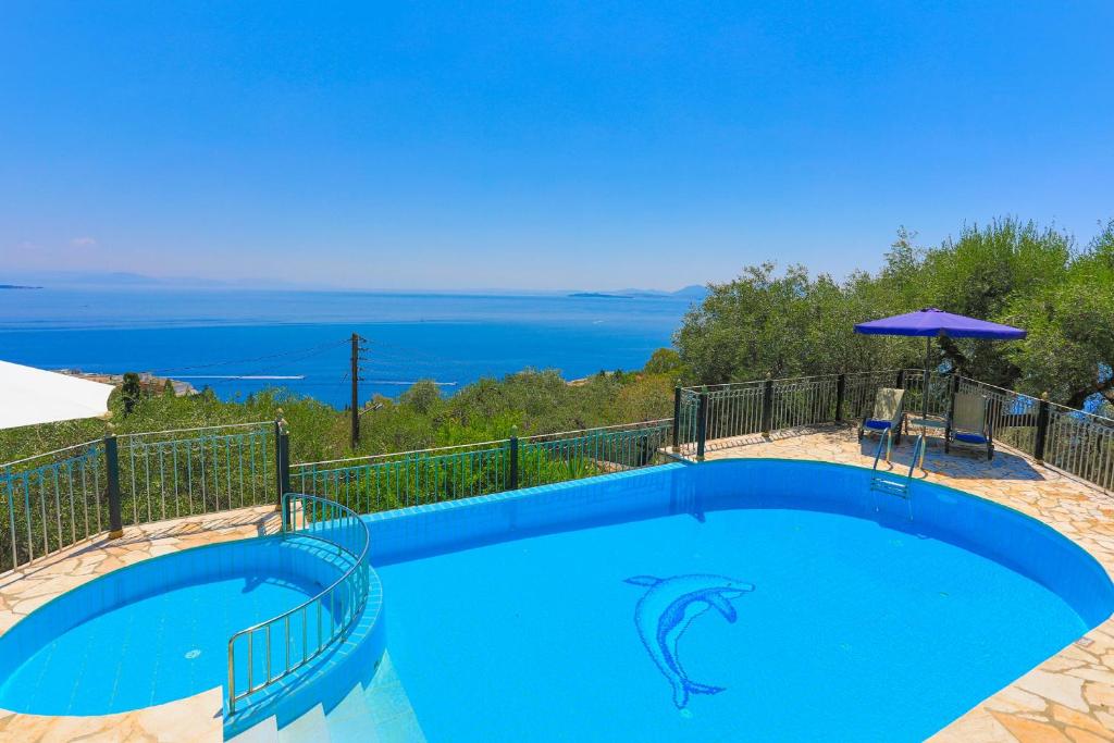 a blue swimming pool with a view of the ocean at Old Stone House in Nisaki