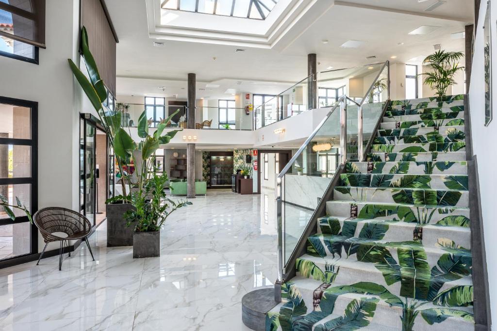 a lobby with a staircase with green plants at Occidental Roca Negra - Adults Only in Agaete