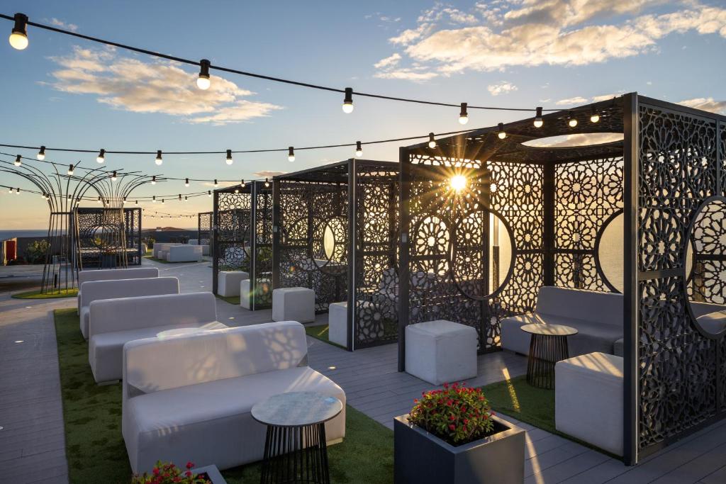 a patio with white chairs and tables and lights at Occidental Roca Negra - Adults Only in Agaete