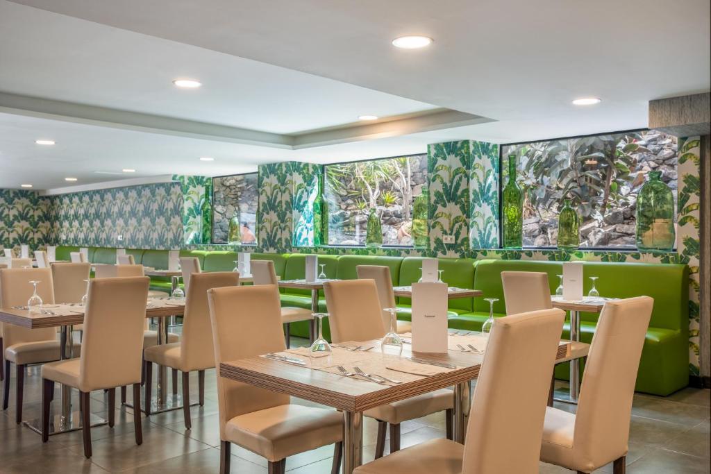 a restaurant with tables and chairs and green walls at Occidental Roca Negra - Adults Only in Agaete