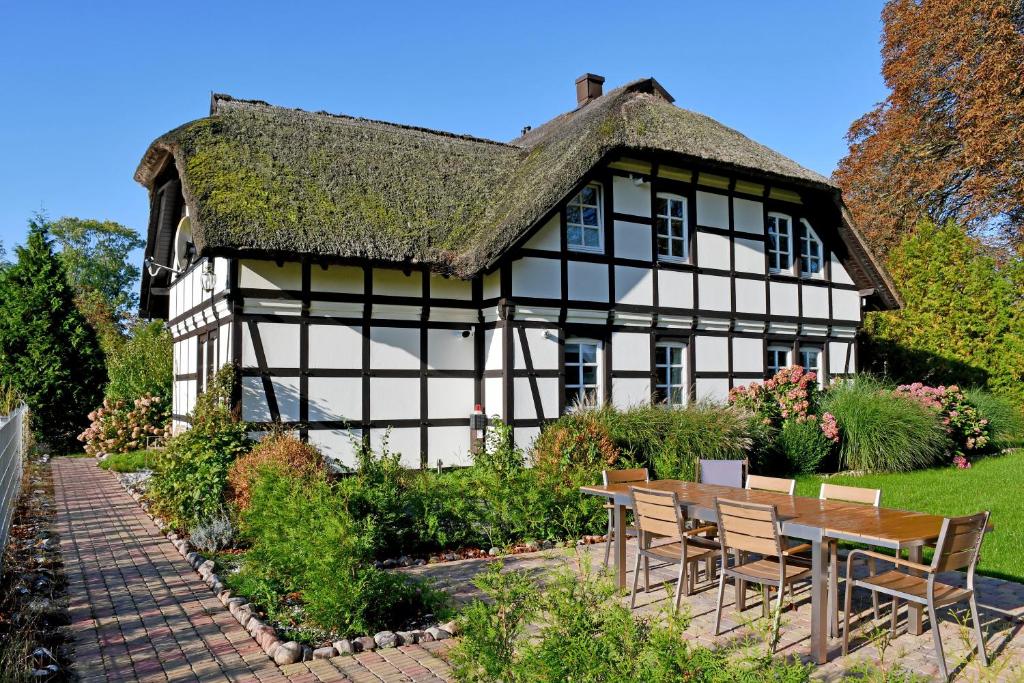 an old black and white house with a table and chairs at Reetdachfachwerkvilla am Wiesengrund in Bergen auf Rügen