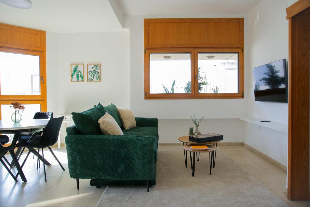 a living room with a green couch and a table at Meir Dizengoff Residence with Shelter in Tel Aviv