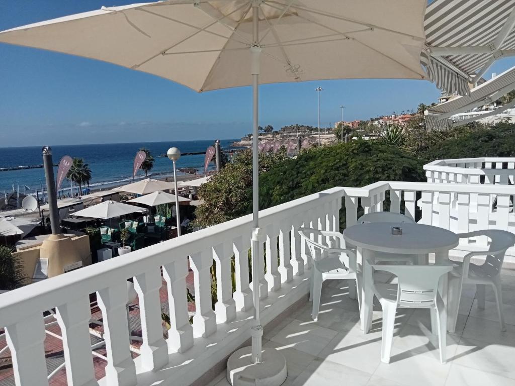 a balcony with a table and an umbrella and the beach at Lagos de Fañabé Beach Resort in Adeje