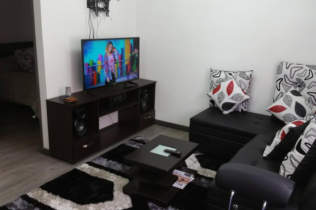 sala de estar con sofá y TV de pantalla plana en Apartamento amoblado Central 148, en Bogotá