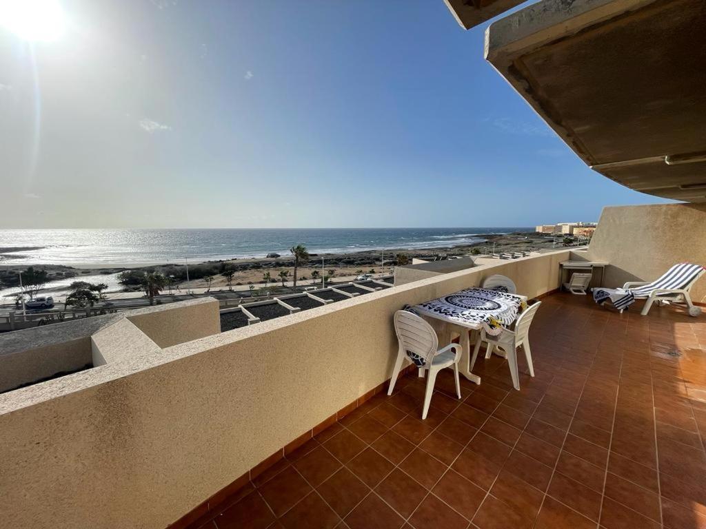 een balkon met een tafel en stoelen en het strand bij Seaview Cabezo flat fully equipped with parking in El Médano