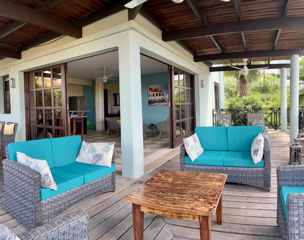 Blue Bay BEACH Villa 27 3-min beach-pool-golf في الخليج الأزرق: فناء به كراسي زرقاء وطاولة خشبية