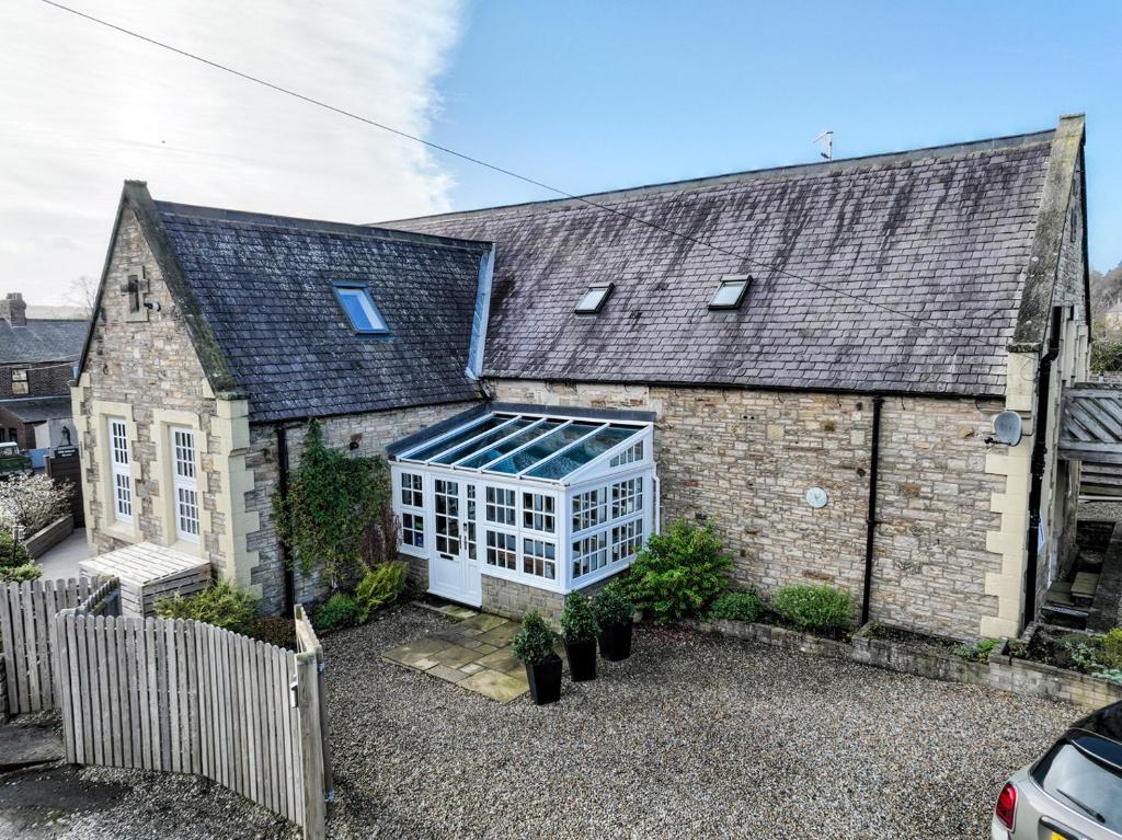 una vieja casa de ladrillo con un invernadero. en The Old School House en Haltwhistle