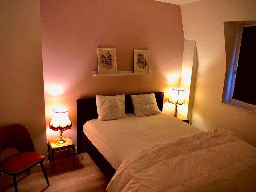 - une chambre avec un lit blanc et deux lampes dans l'établissement Le Saint Laurent, à Liège