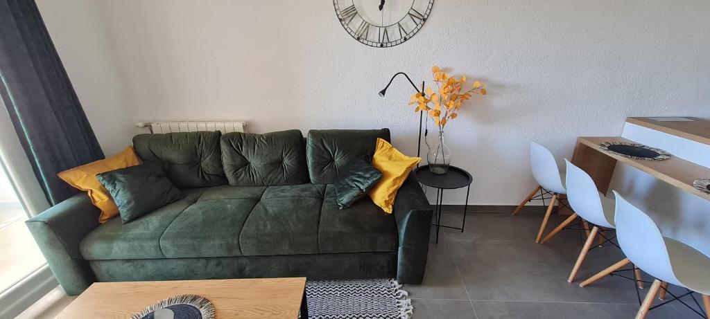 a living room with a green couch and a clock on the wall at Holiday Park Lu-Ka in Pakoštane