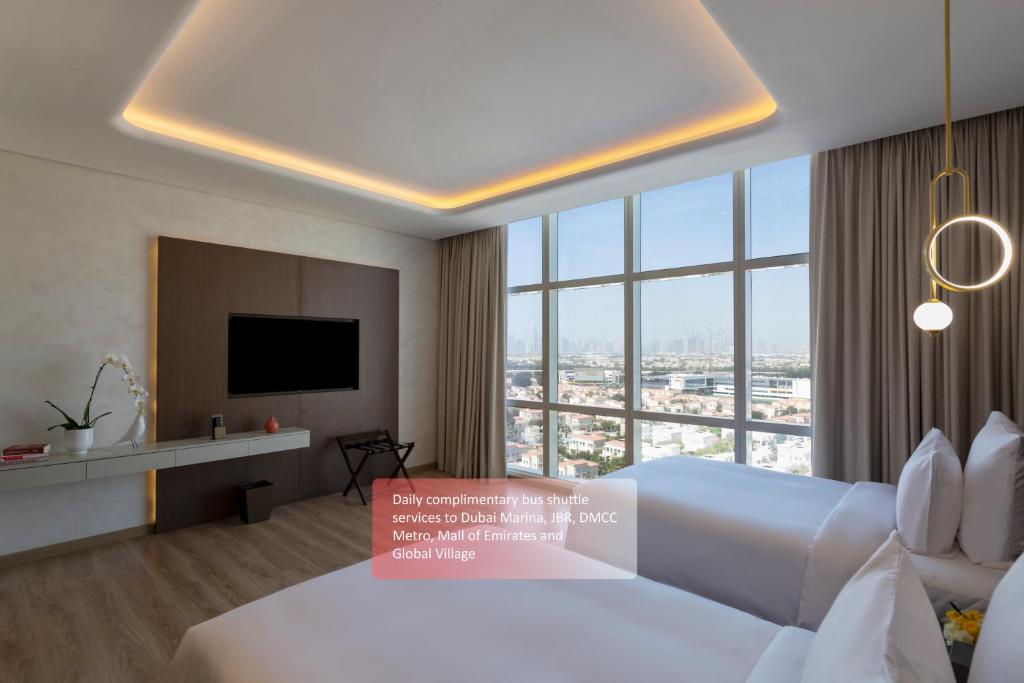 a hotel room with a bed and a large window at Movenpick Jumeirah Village Triangle in Dubai