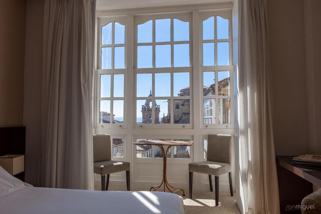 a bedroom with a large window and a table and chairs at Hotel San Miguel in Santiago de Compostela