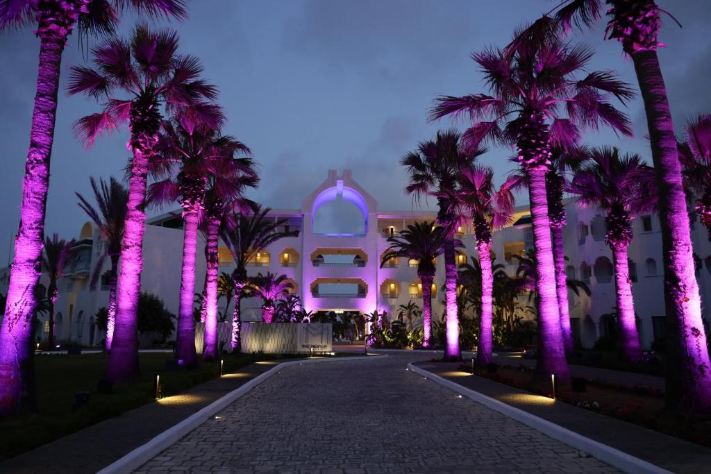 un edificio con palmeras y luces púrpuras en The Mirage Resort & SPA en Hammamet