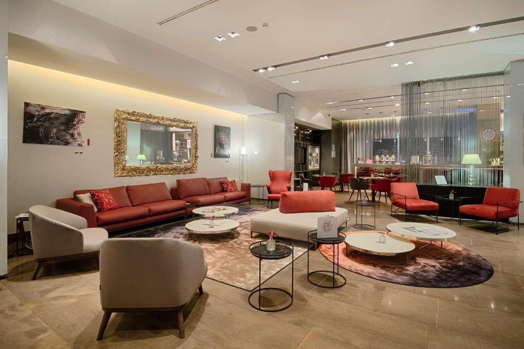 a living room with a couch and chairs and tables at NH Collection Milano President in Milan