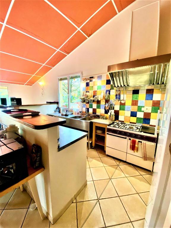 a large kitchen with colorful tiles on the wall at CHAMBRES D&#39;HOTES 2 à 4p ou GITE DE GROUPE 15p, 7 ch, 6 sdb, parc et salle de réception in Villeneuve-de-Berg