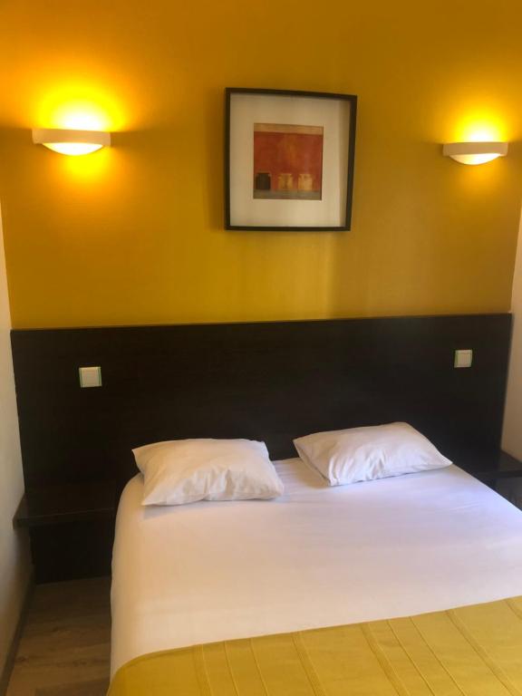 a bedroom with a bed with two white pillows at Hôtel De Paris in Dijon