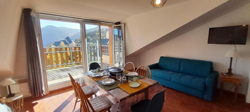 a living room with a table and a couch and a large window at Chez Lulilo in Ax-les-Thermes