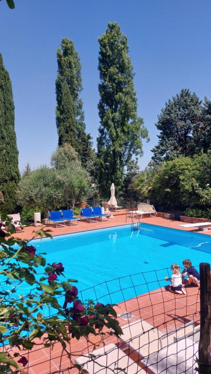 フィレンツェにあるFattoria Il Milione Agriturismoの青い椅子と木々が並ぶ大きなスイミングプール