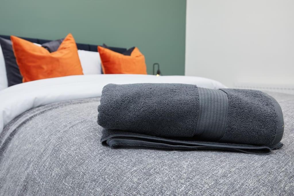 une pile de serviettes assises au-dessus d'un lit dans l'établissement Sleek & Stylish Modern 4-Bedroom Urban Retreat, à Leicester