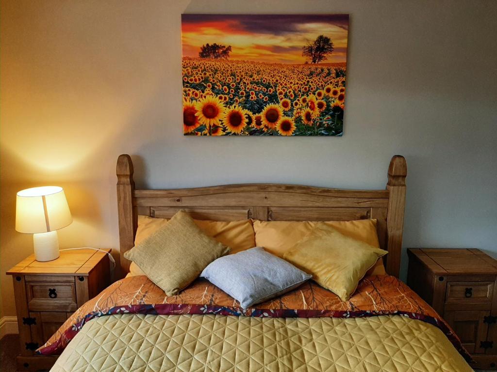 a bedroom with a bed and a painting of a field of sunflowers at Maria`s Garden House in Ollerton