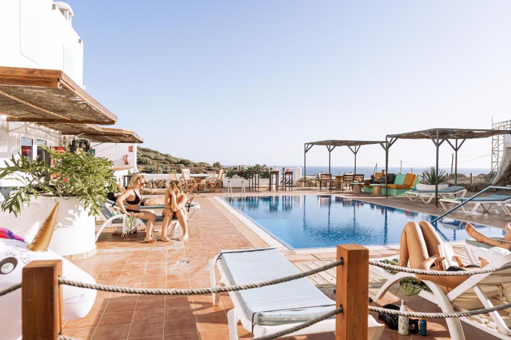 um grupo de pessoas sentadas em torno de uma piscina em um hotel em The Tree House Tenerife em El Médano