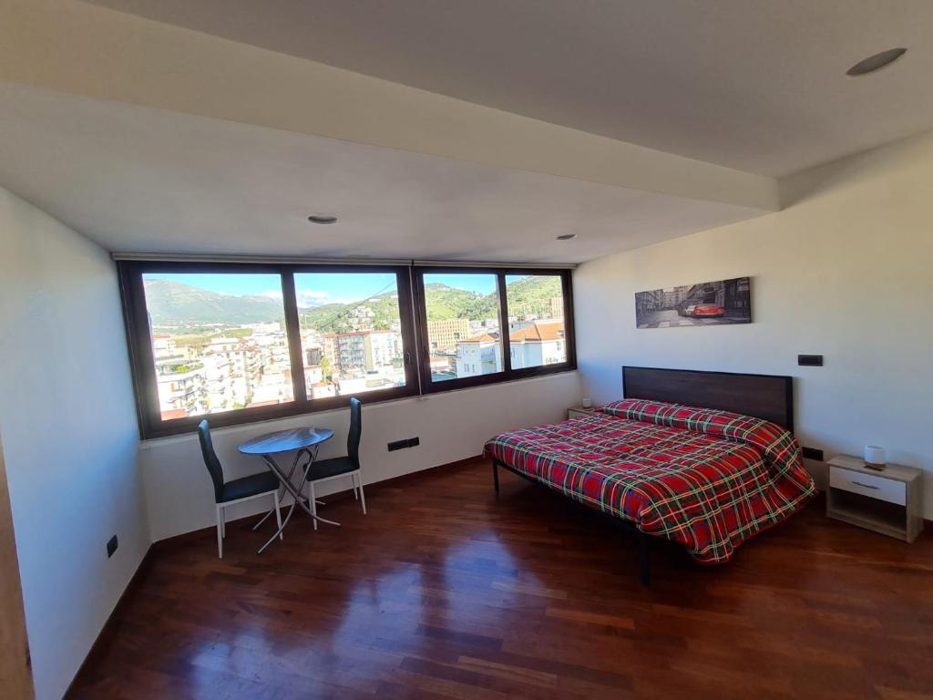 um quarto com uma cama e uma mesa e algumas janelas em La Grotta Stazione em Salerno