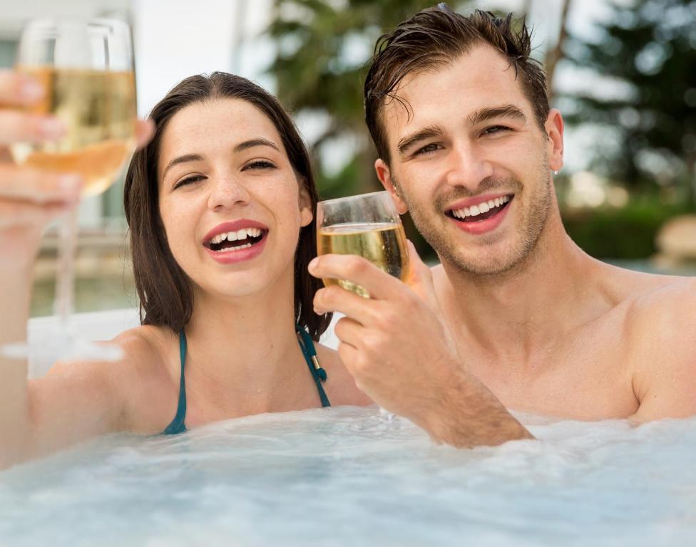 un homme et une femme dans une piscine avec un verre de vin dans l'établissement Gite-ardennes & wellness - Ovifat - Orchidées 8 pers & Coquelicots 7 pers, à Ovifat