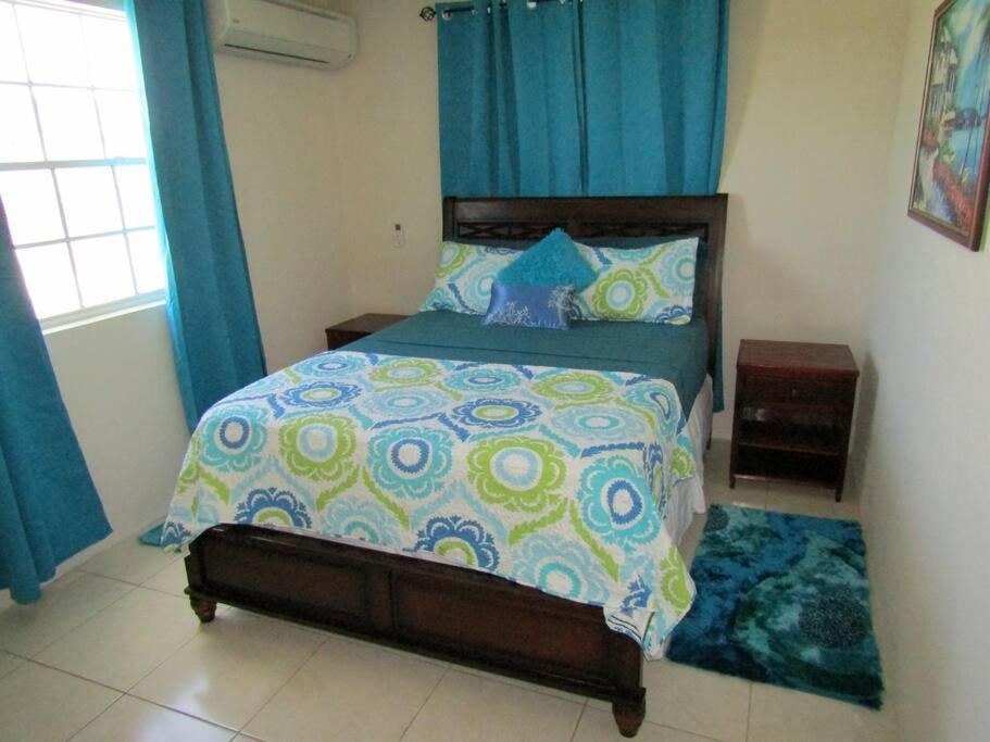 een slaapkamer met een groot bed en blauwe gordijnen bij Apt Turtle Beach your home at the beach in Christ Church