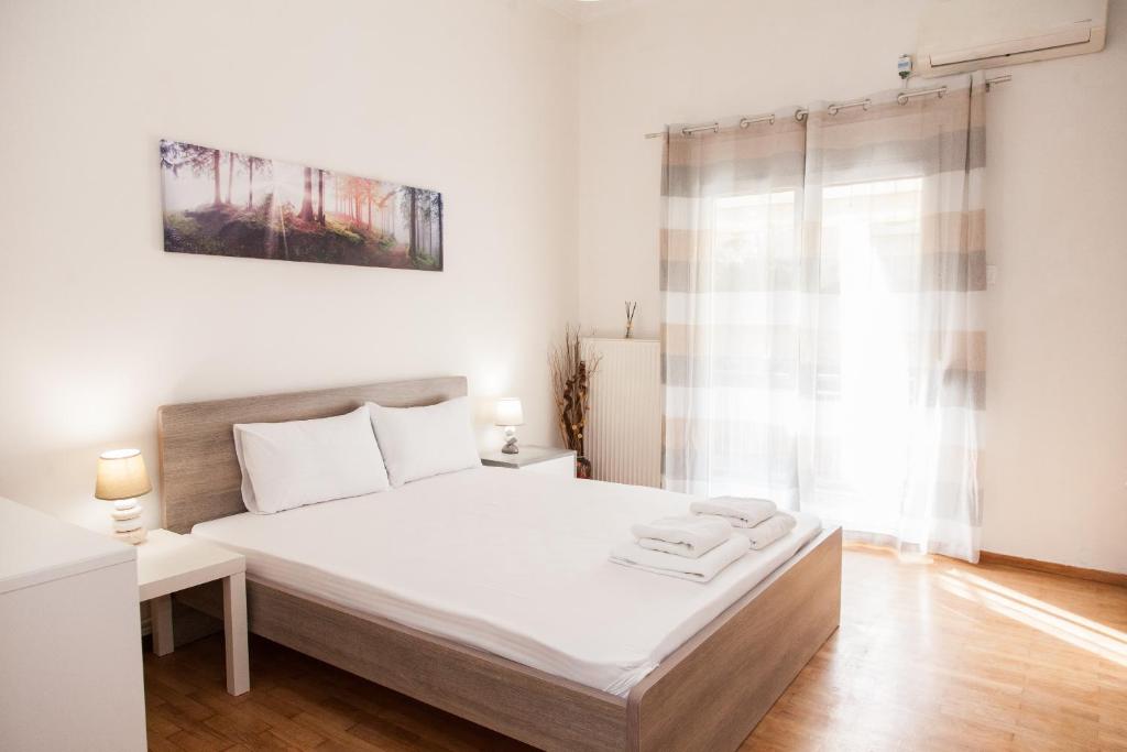 a white bedroom with a bed and a window at Cozy apartment near Stavros Niarchos Park in Athens