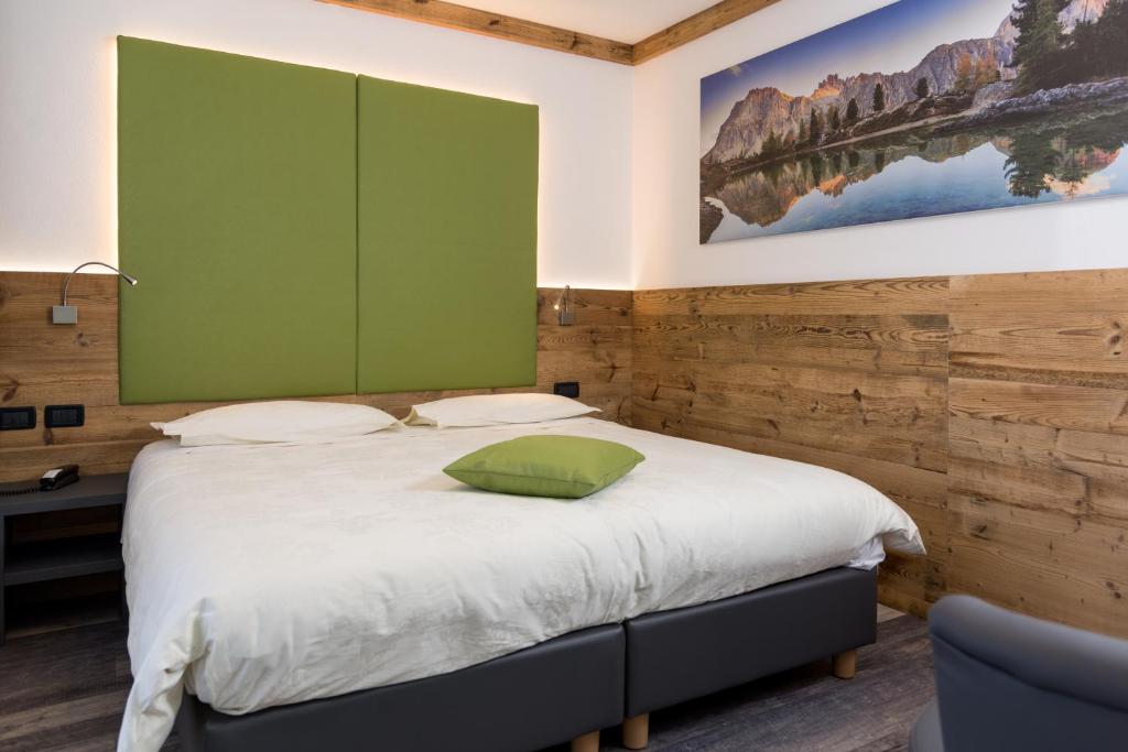 a bedroom with a bed with a green accent wall at Hotel Chalet Sas Morin in Pozza di Fassa