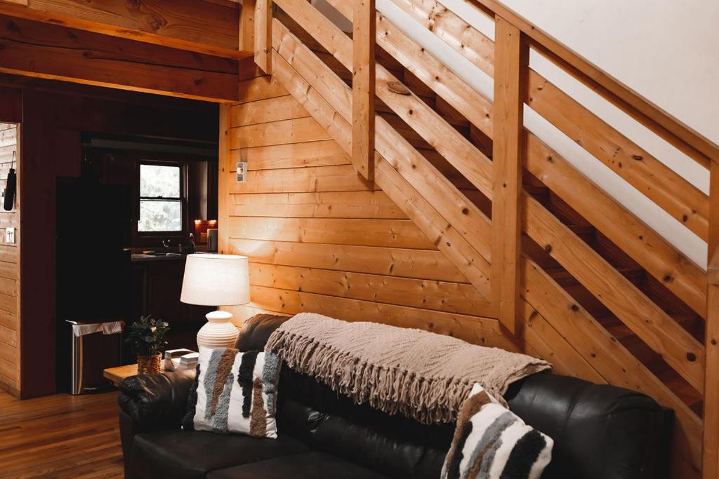 un sofá de cuero en una habitación con una pared de madera en Wolf Creek Cabin at 36 North - Hot Tub, en Purlear