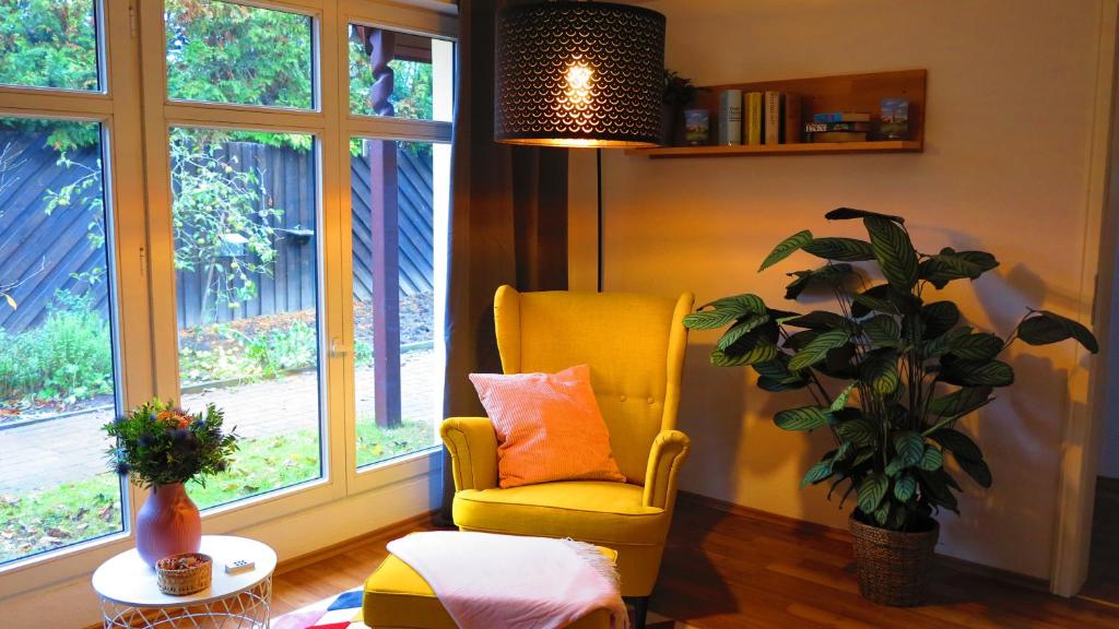 a living room with a yellow chair and a plant at Ferienhaus Gute Laune in Lichtenhagen