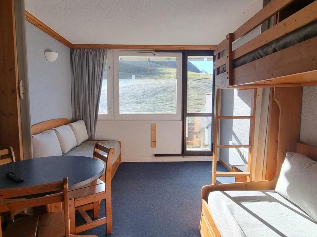 Cette chambre comprend un lit, une table et des lits superposés. dans l'établissement Studio lumineux divisible - Pied des pistes - Balcon exposé sud - FR-1-181-2608, à Aime La Plagne