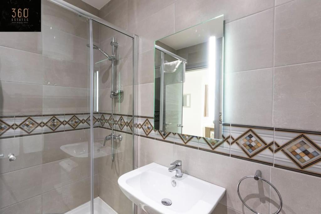 a bathroom with a sink and a shower and a mirror at Spacious, beautiful central penthouse with BBQ by 360 Estates in Tal-Pietà
