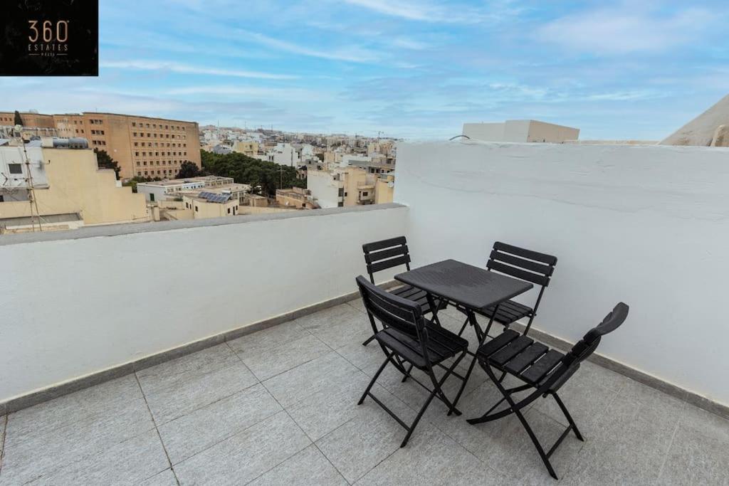 a table and chairs on the roof of a building at Spacious, beautiful central penthouse with BBQ by 360 Estates in Tal-Pietà