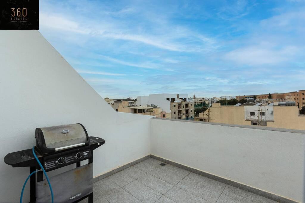 a grill on a balcony with a view of a city at Spacious, beautiful central penthouse with BBQ by 360 Estates in Tal-Pietà