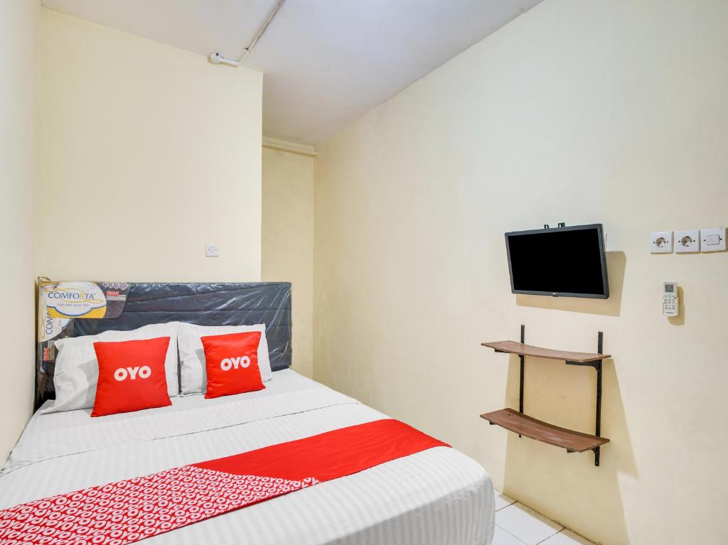 Schlafzimmer mit einem Bett mit roten Kissen und einem TV in der Unterkunft SUPER OYO 591 Mn Residence Syariah in Jakarta